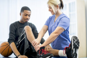 Physical therapist treating a young adult with a leg injury.